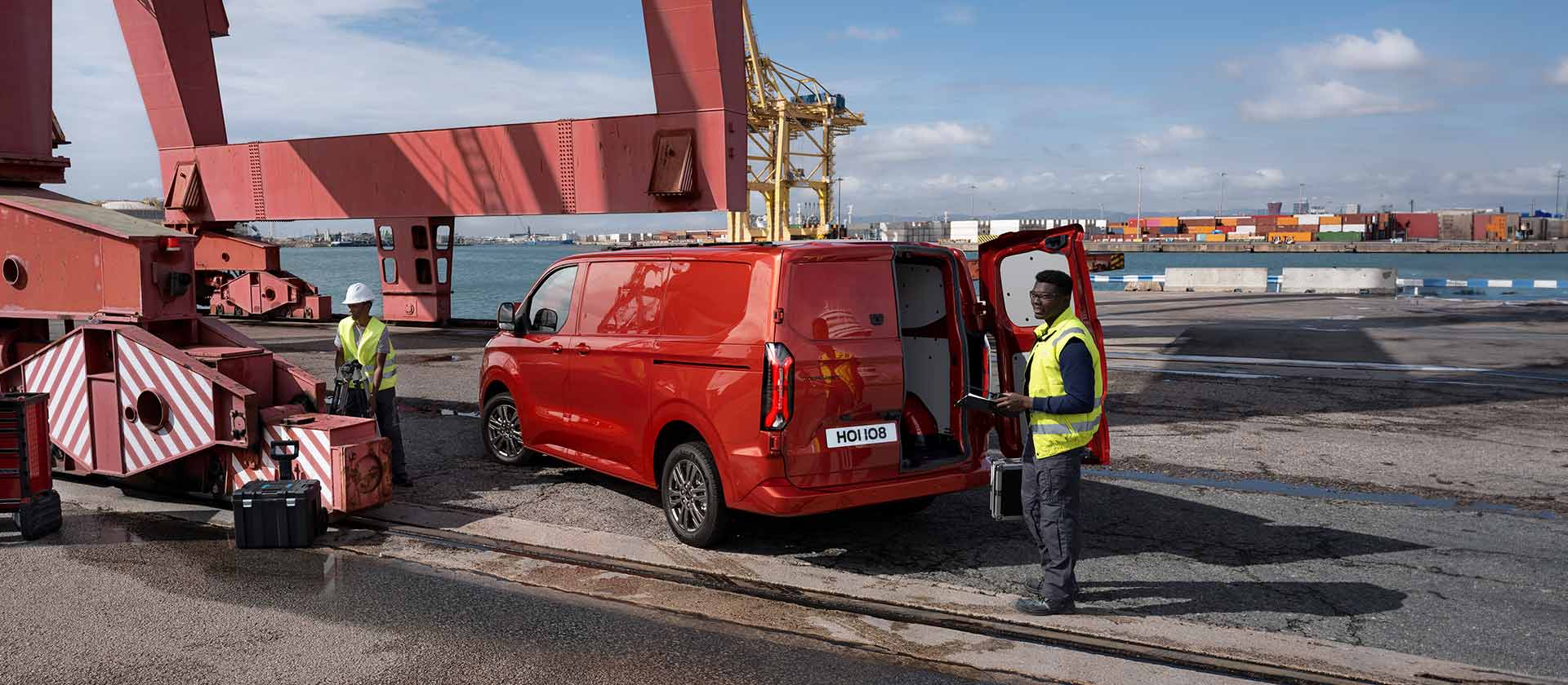 Rød Ford Transit Custom-varebil ved et havneområde.