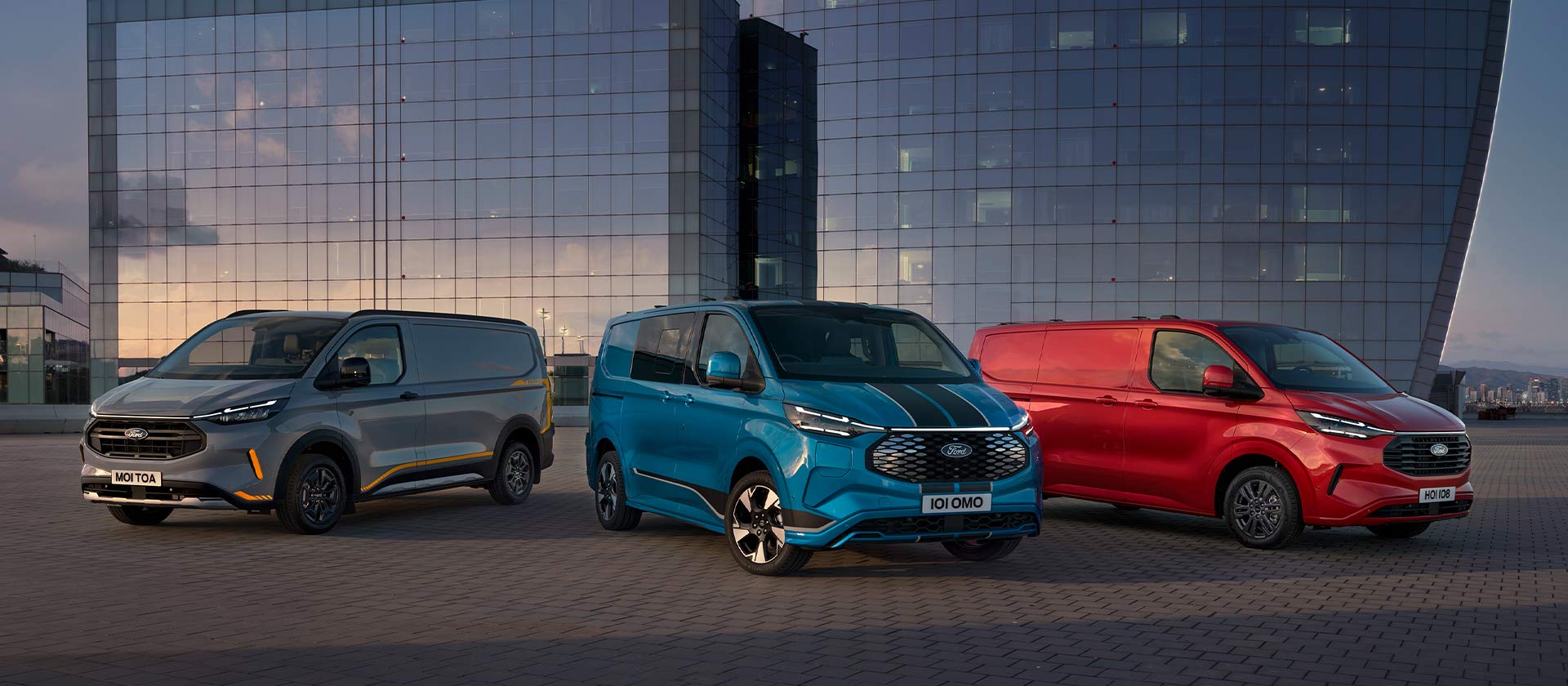 Tre Ford Transit Custom Sport-varebiler i grått, blått og rødt står parkert.