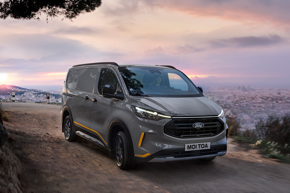 Grå Ford Transit Custom Trail-varebil med gule detaljer.