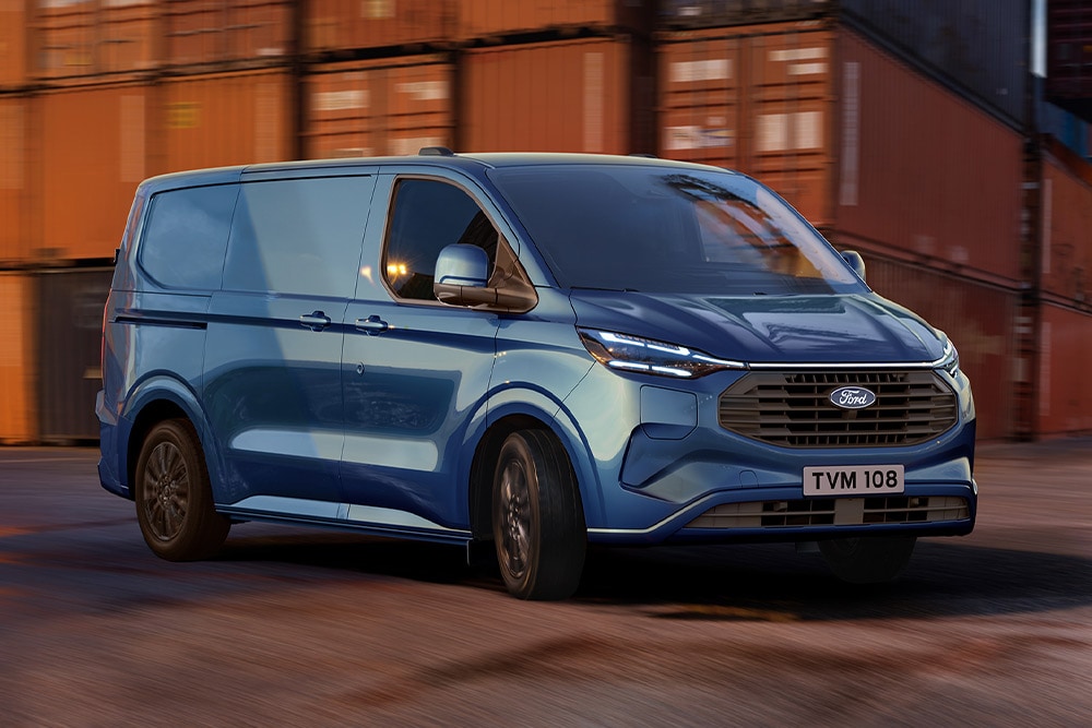 Blå Ford Transit Custom ladbar hybrid kjører gjennom et skipsverft.