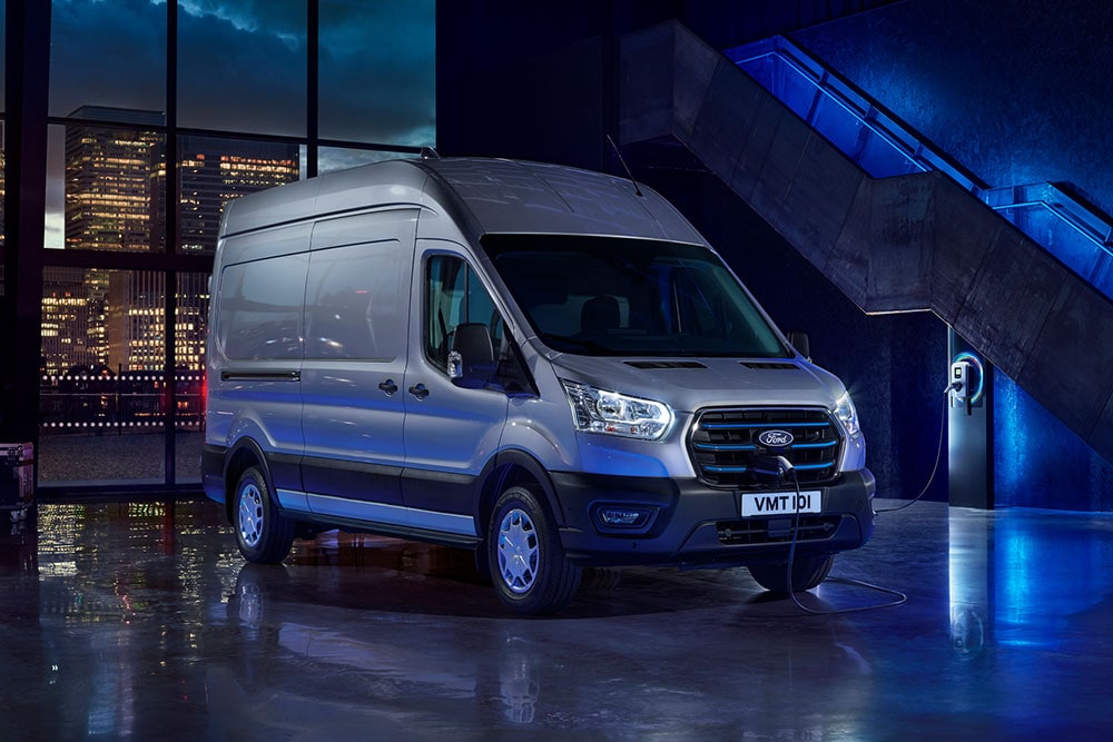 Ford E-Transit varebil parkert i nærheten av et ladepunkt.
