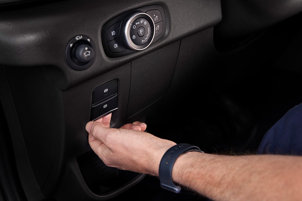 Nærbilde av en hånd som trykker på en knapp på dashbordet til en Ford E-Transit elektrisk varebil.