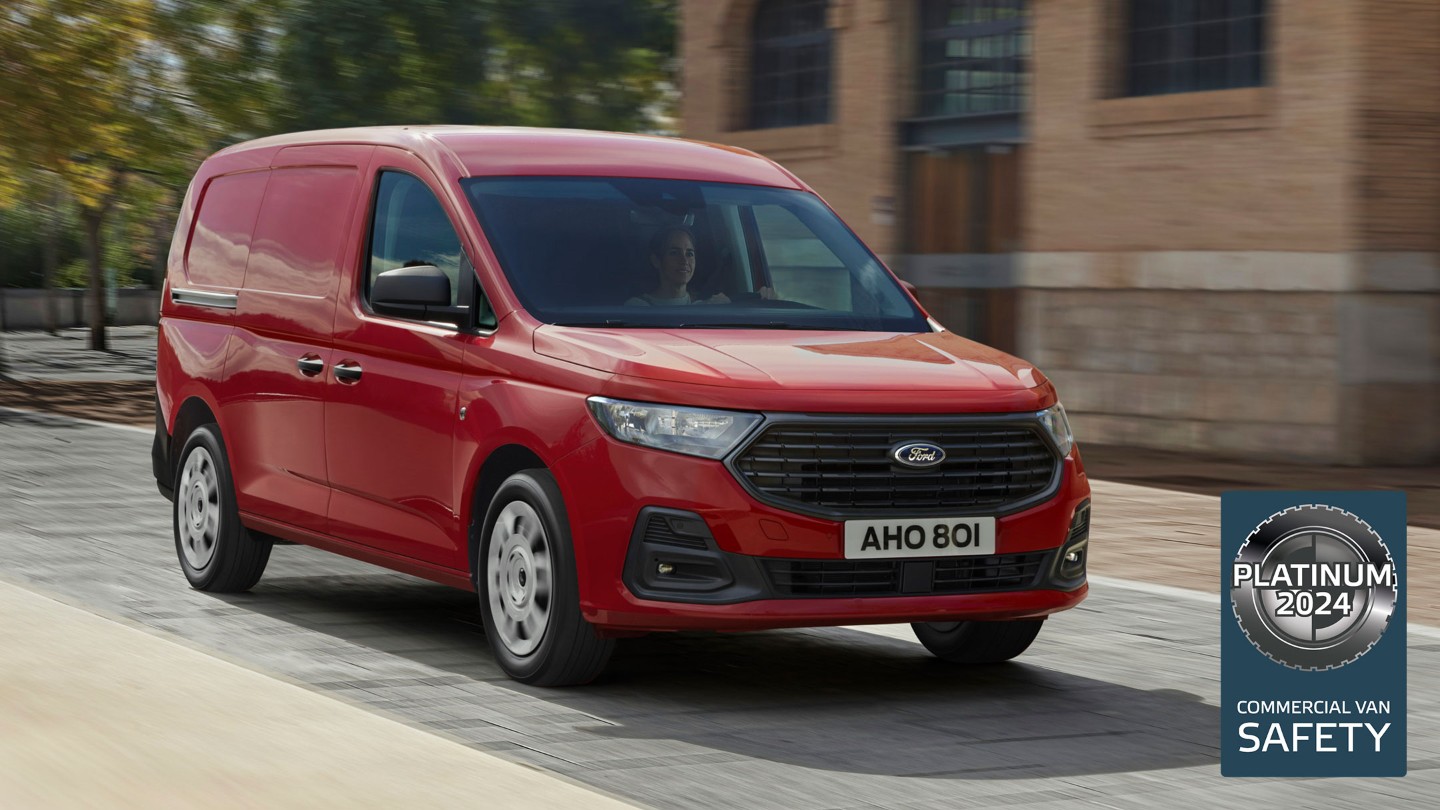 Splitter nye Ford Transit Connect Trend i Maple Red kjører nedover en gate, med frontgrillen og de automatiske frontlyktene synlig. 