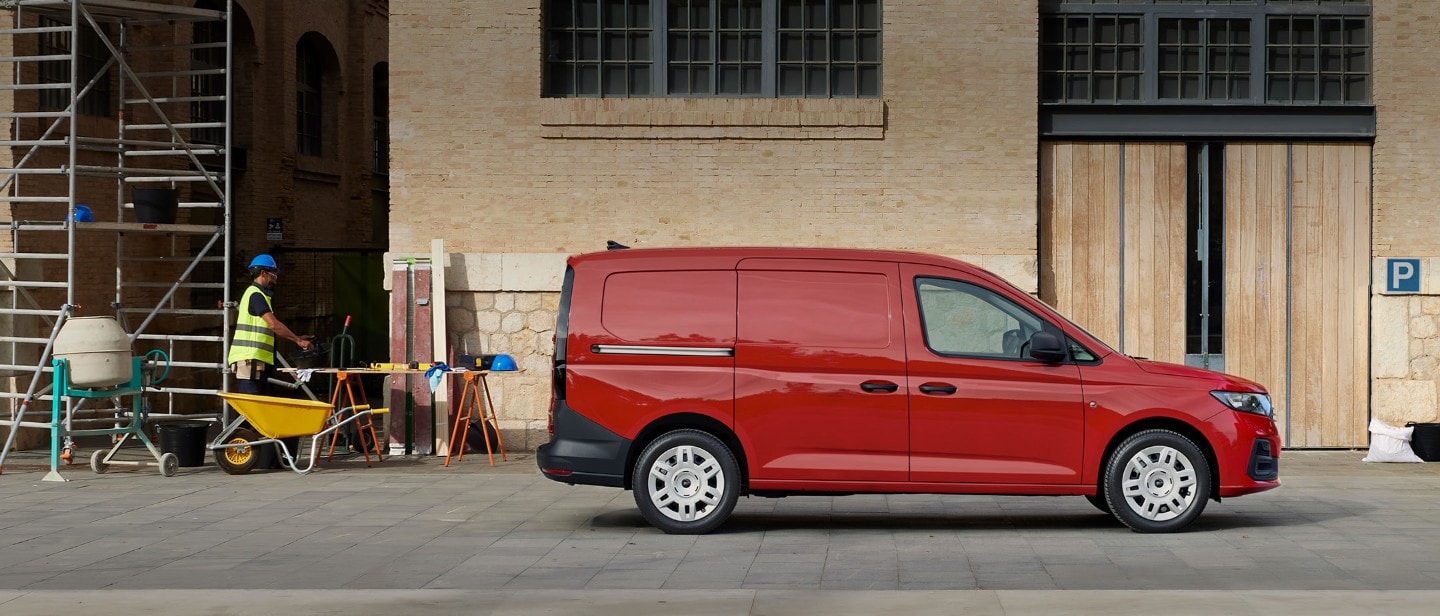 Visning av sidelastedørene på en splitter ny Ford Transit Connect i Maple Red som står parkert på en byggeplass.