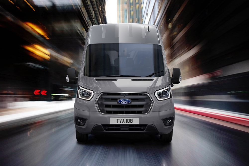 Visning forfra av en Ford Transit-varebil som kjører i byen.