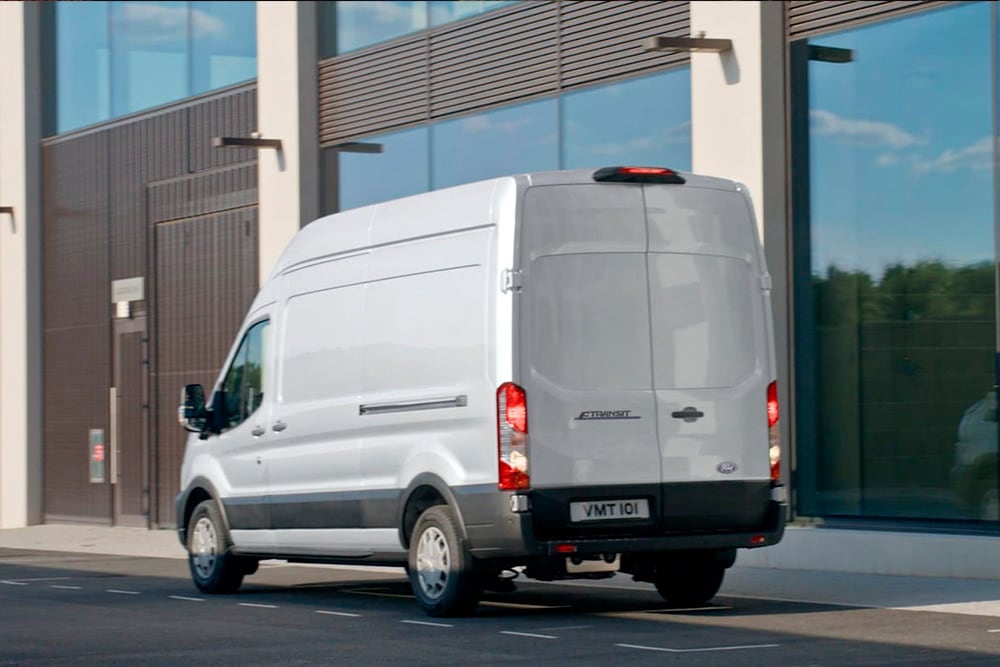 Visning bakfra av en sølvfarget  Ford Transit varebil parkert på en bygate. 