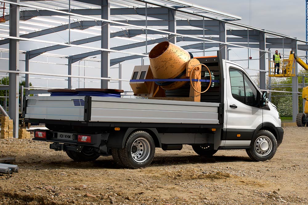 Ford Transit Chassis Cab som frakter en sementblander i lasterommet parkert på en byggeplass. 