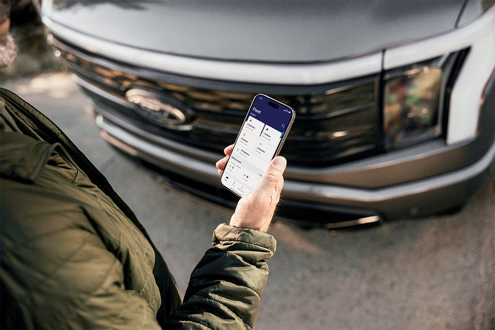 En mann som sjekker smarttelefonen sin foran en Ford Ranger.