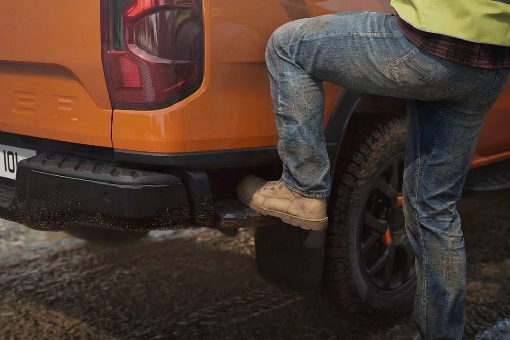 En arbeider som går opp på det integrerte bakre stigtrinnet på Ford Ranger Wildtrak.