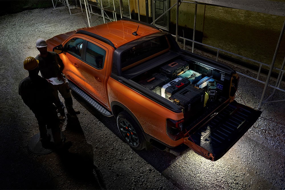Visning ovenfra av en oransje Ford Ranger Wildtrak om natten med utvendig sonebelysning.