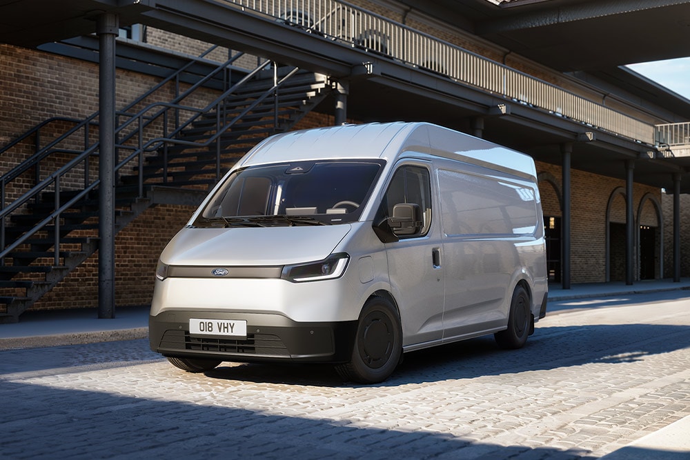 Hvit Ford Transit City® L2H2-varebil parkert foran en mursteinsbygning.