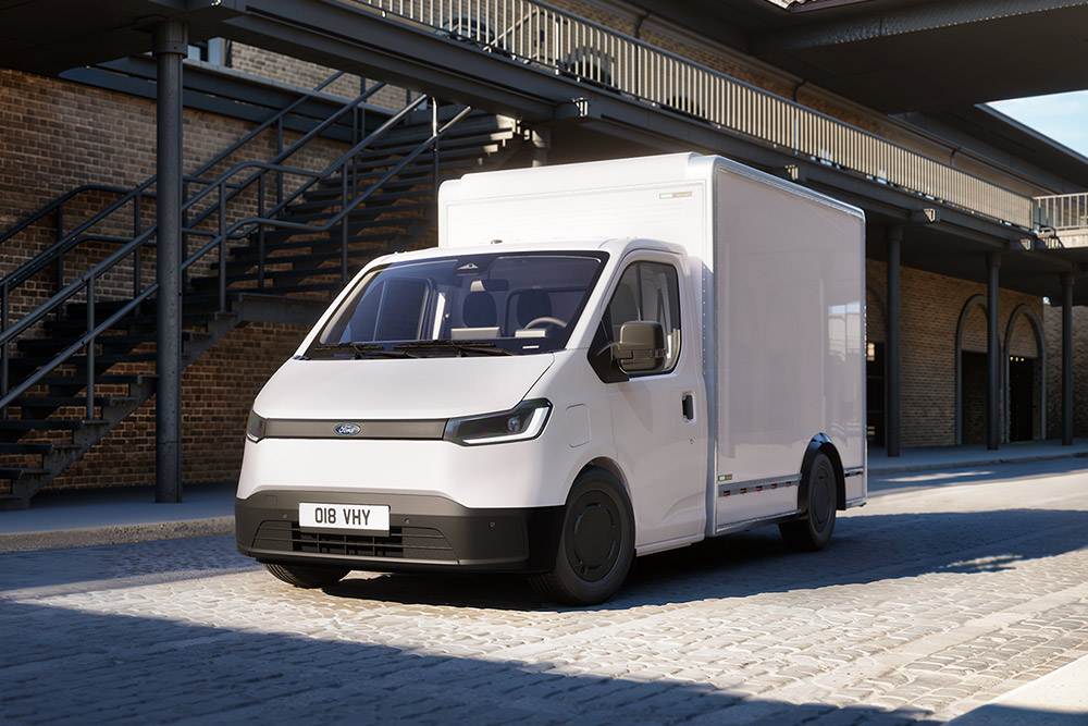 Hvit Ford Transit City® Chassis varebil parkert foran en mursteinsbygning.