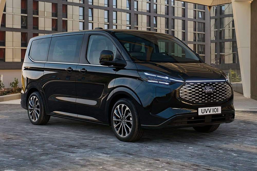 Svart Ford Pro Transit parkert foran en moderne bygning.