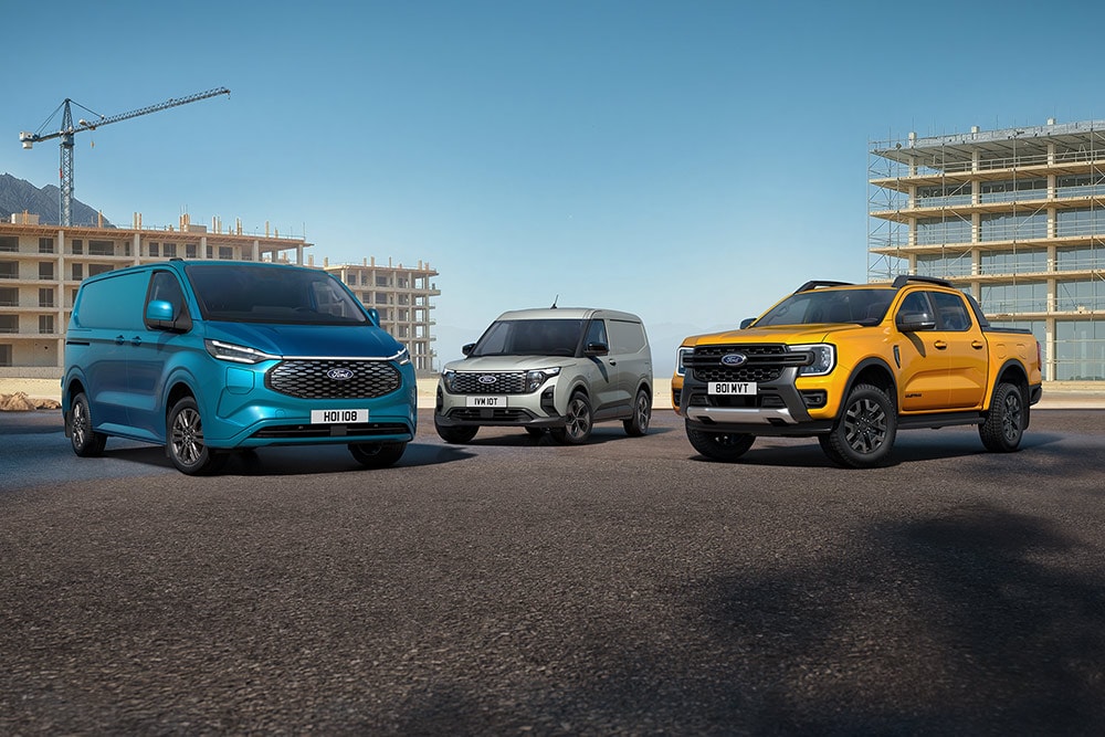 En samling Ford-kjøretøy parkert foran en byggeplass.