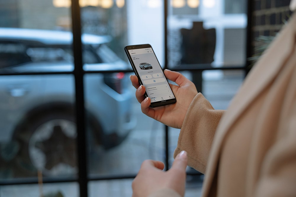 En person som holder en smarttelefon som viser Ford-appen med informasjon om flåteadministrasjon.