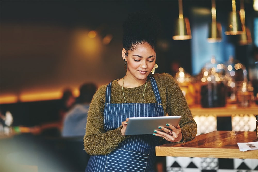 En restauranteier sjekker firmabilavgiften sin på et nettbrett.