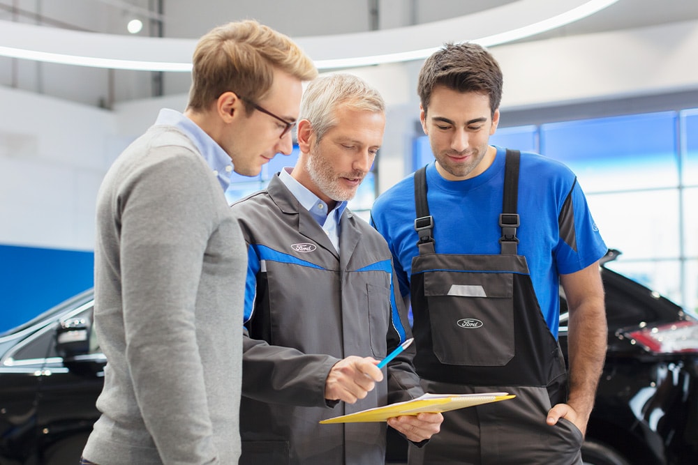 Tre eksperter diskuterer hyllevare kjøretøyalternativer ved et Ford Transit Centre.