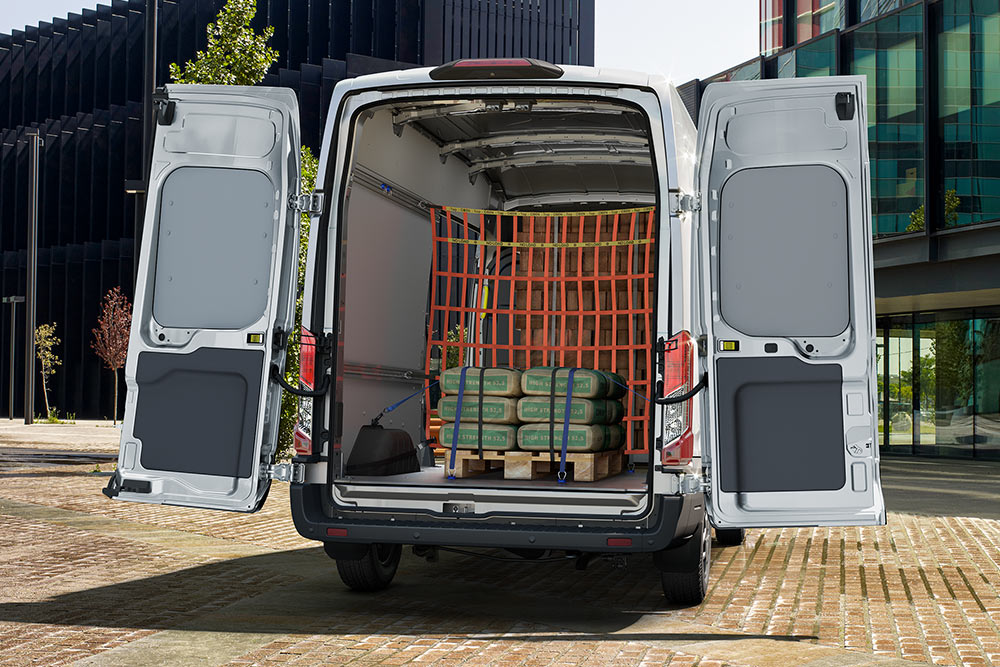 En bakfra-visning av innsiden av en hvit Ford varebil parkert nær kontorbygninger.