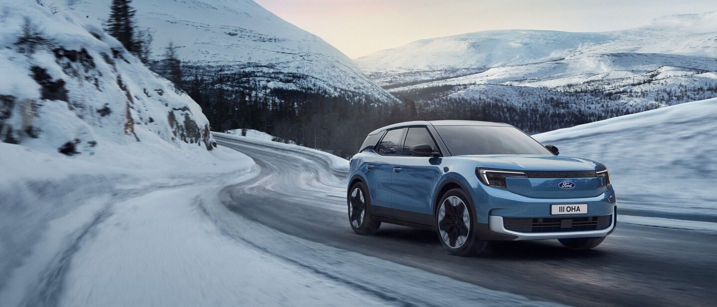 Blue all-electric Ford Explorer driving on a snowy road