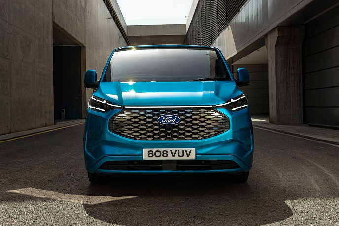 En blå elektrisk Ford E-Transit Custom varebil sett forfra.