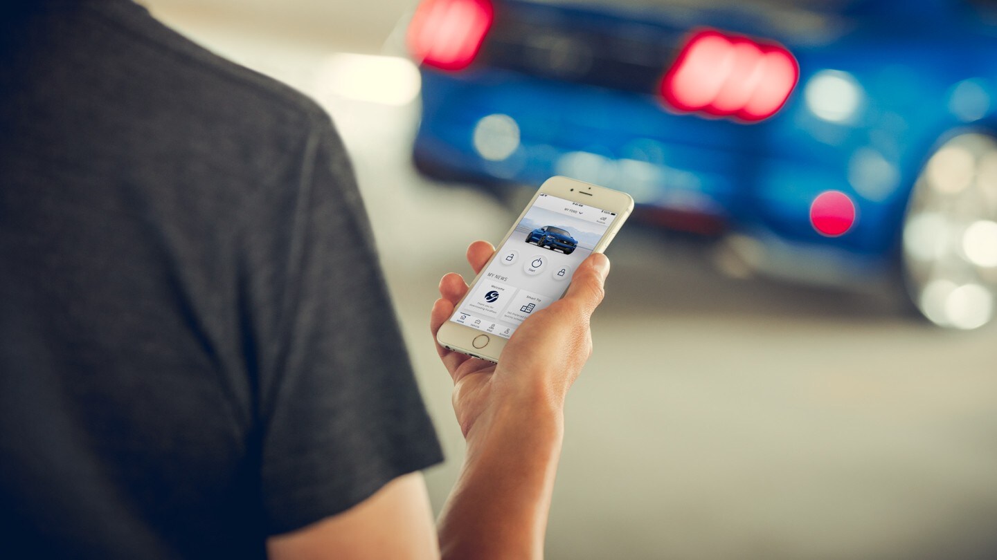 Man looking at smartphone with Ford app displayed