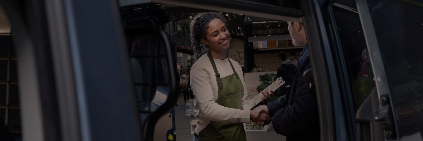 Two people greeting each other viewed from open Ford Van door